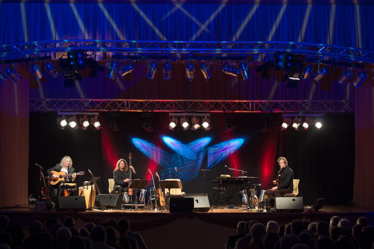 Live-Band auf der Bühne mit violetter Effektbeleuchtung und Hintergrundprojektion